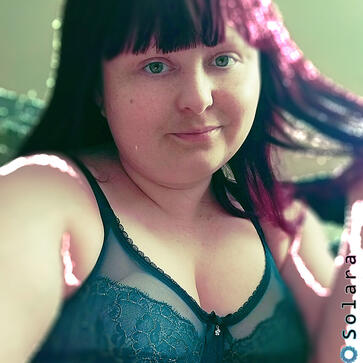 Devon smiles while twirling her red hair, in a sparkly green bra